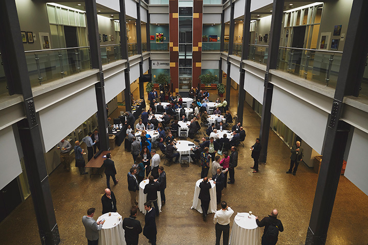 People stand by tables with white tablecloths at the MMRI open house in 2019.