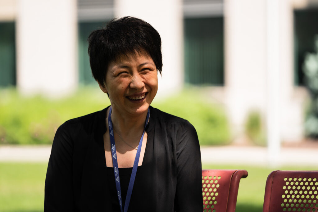 Wenbo laughing on a bench outside on campus