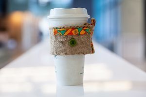 A coffee cup with a homemade burlap sleeve.