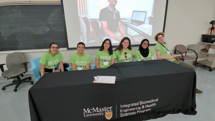iBioMed ambassadors sit along a table in green shirts