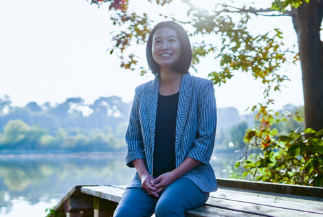Zoe Li sits on a bench by water