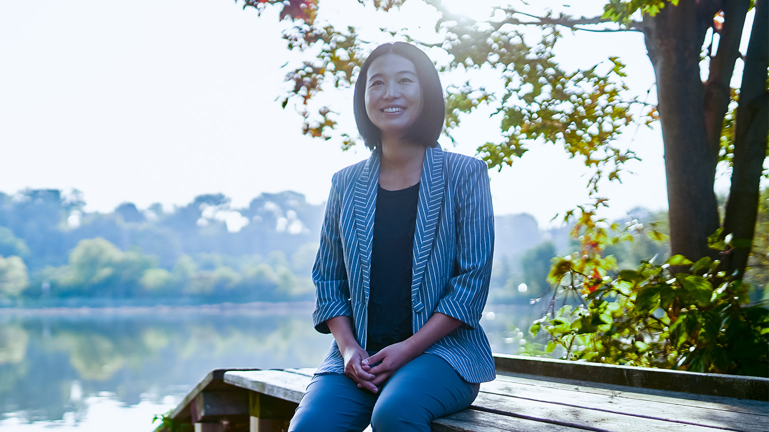 Zoe Li sits on a bench by water