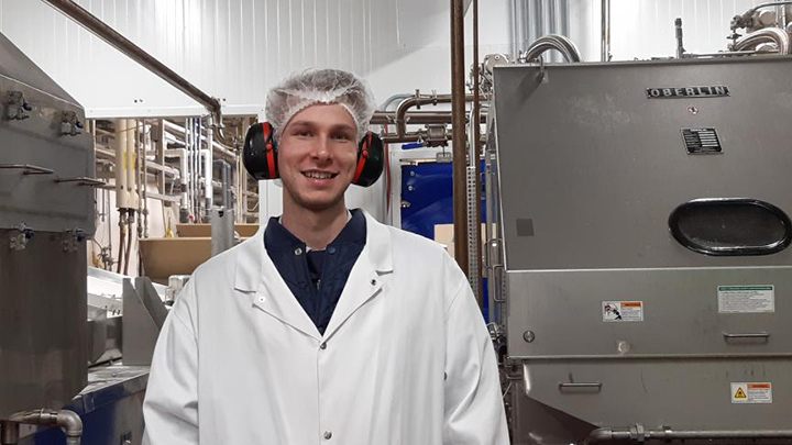 Ryan McMinn in a lab wearing a hair net, headphones and lab coat