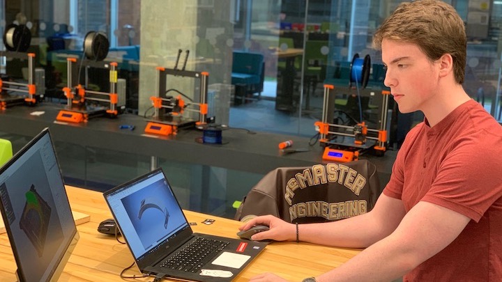 Alec Fernback works on 3d models of a face shield on a laptop