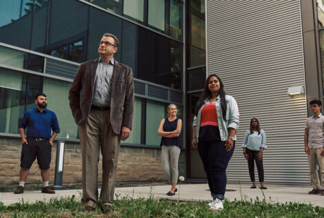 Cam Churchill and Grand Challenges crew stand outside JHE all looking off in the distance in different directions