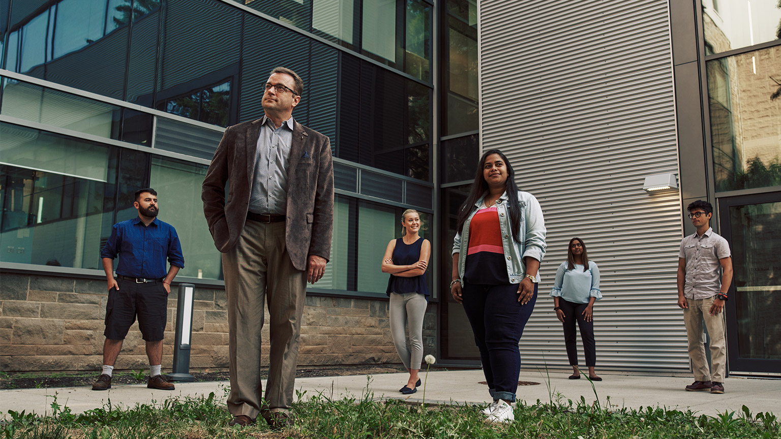 Cam Churchill and Grand Challenges crew stand outside JHE all looking off in the distance in different directions