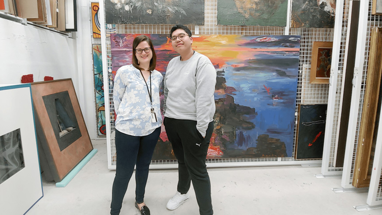 two people pose in room filled with art work