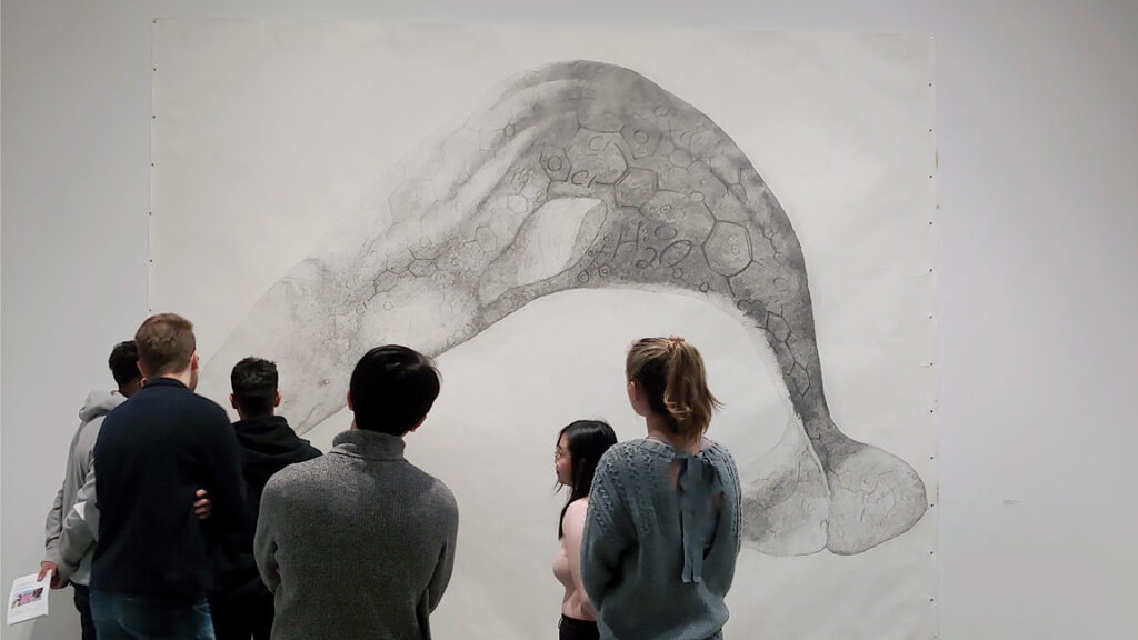 group of students admire sketch of whale