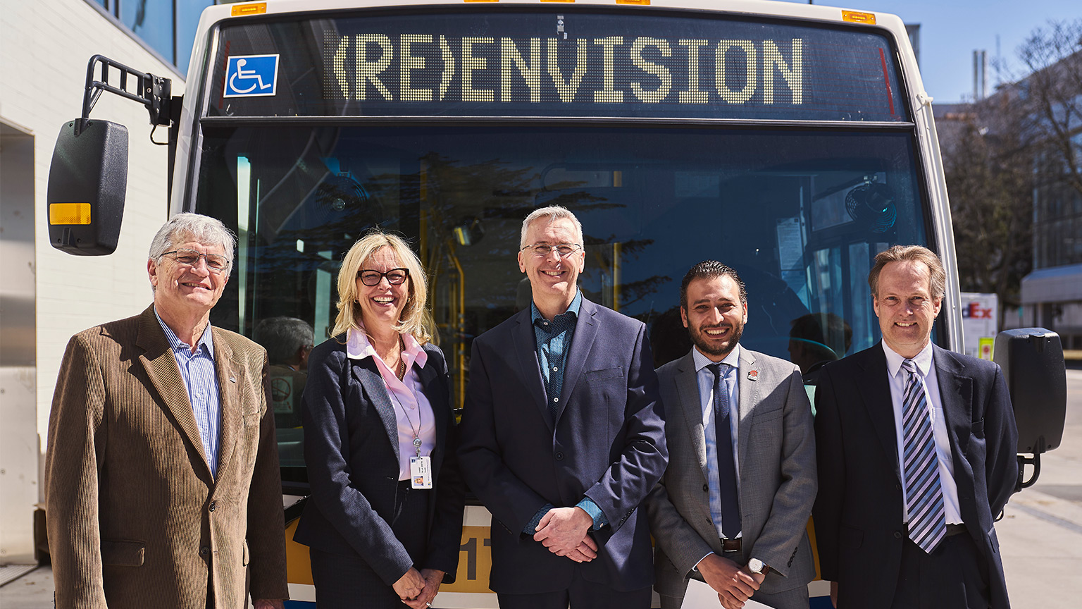 group of people posing in front of a Hamilton City bus.