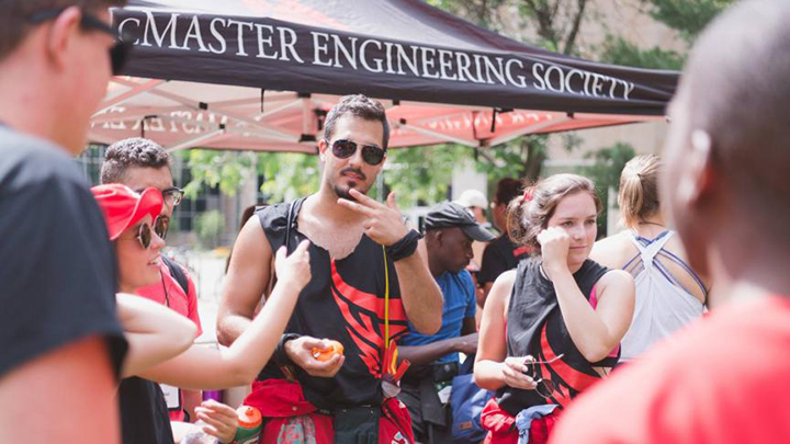Vincent Popovich wearing sunglasses in front of a McMaster Engineering Society tent.