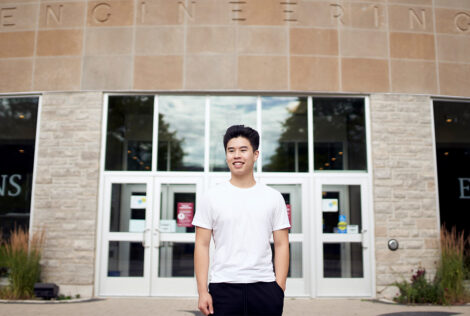 David Chung poses outside the JHE entrance doors with one hand in their pockets