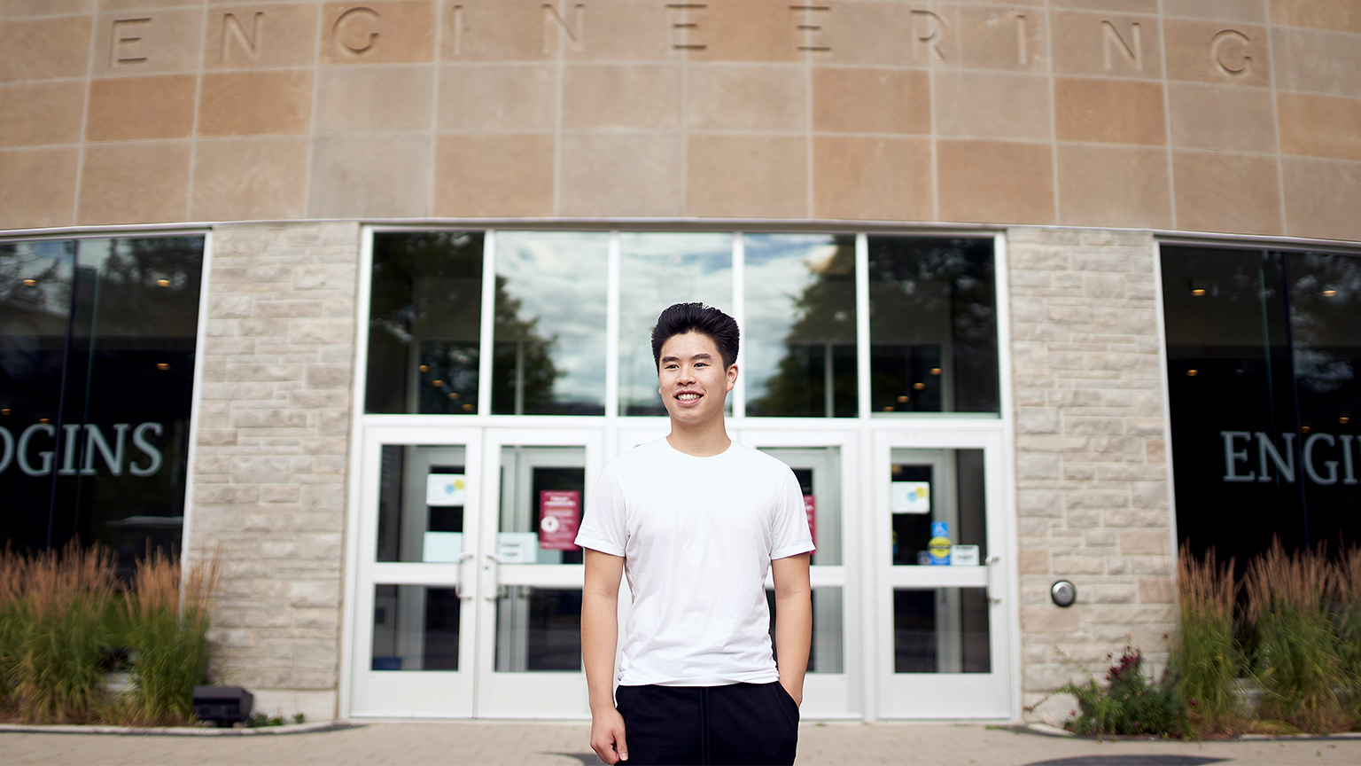 David Chung poses outside the JHE entrance doors with one hand in their pockets