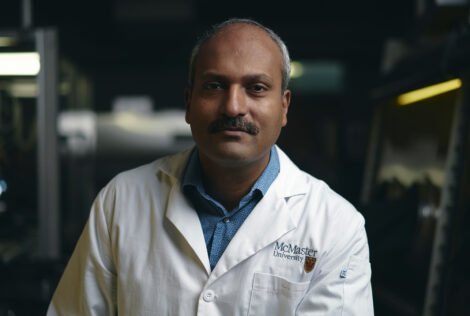 Ravi sits in a lab wearing a white mcmaster lab coat