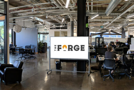 Inside the Forge, a whiteboard bears it's logo with people sitting at tables