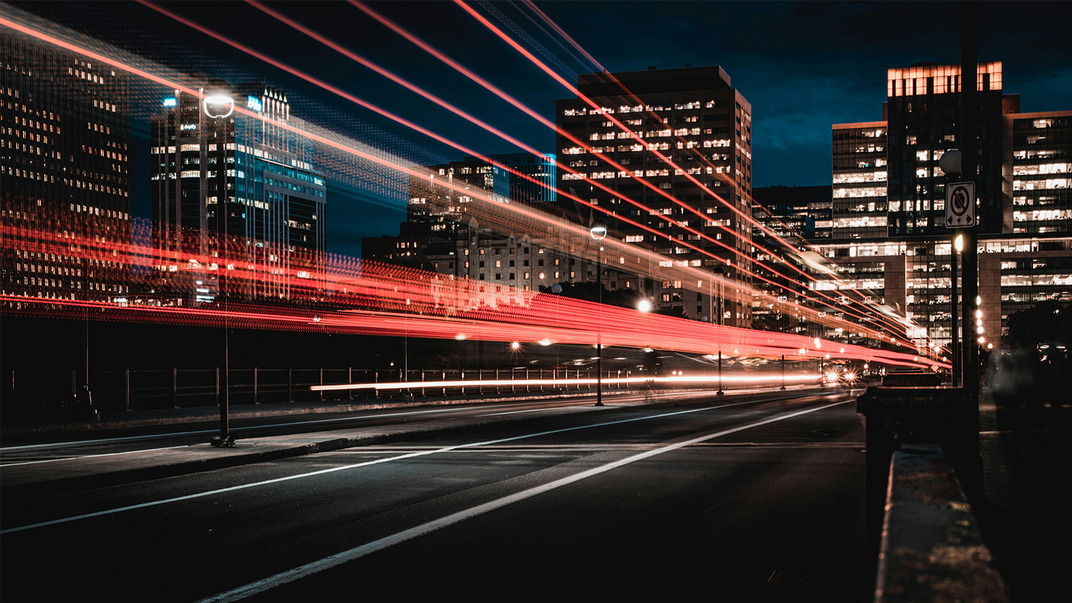 A city street at night with a light effect showing lines of red light going down the street