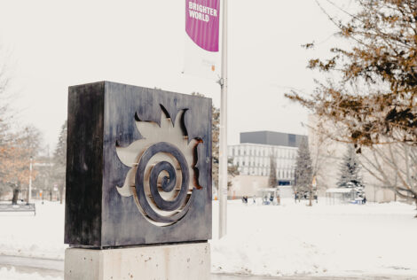 A fireball sign outside Hatch with a snow covered campus in the background