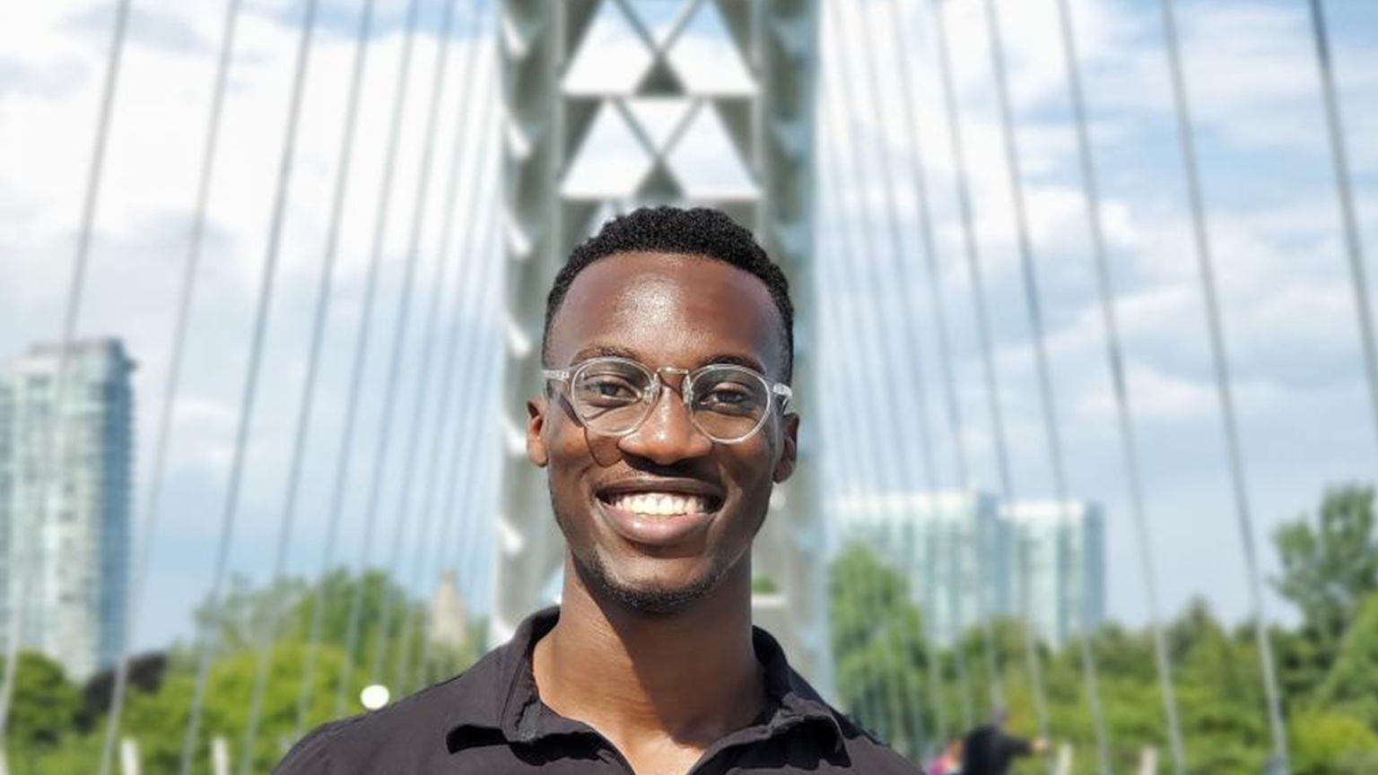 Rotimi poses in front of a suspension bridge