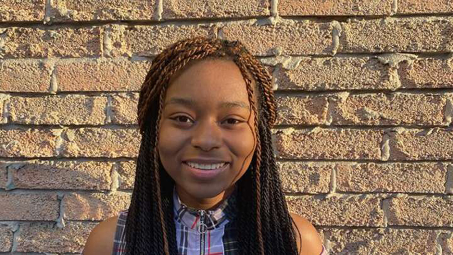 Shunae Mickle poses in front of a brick wall