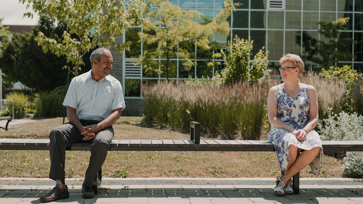 Alison Fox-Robichaud and Ravi Selvaganapathy sit on bench far apart looking at each other