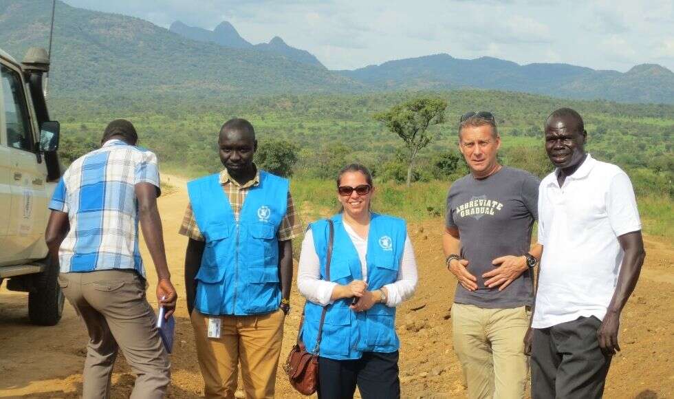 Sogol stands with people while wearing a blue WFP vest
