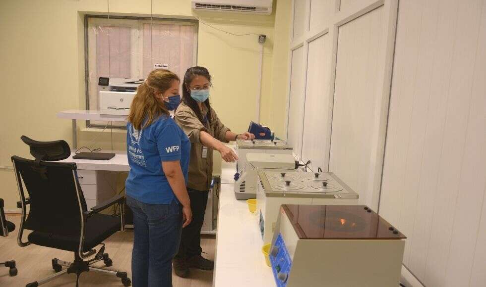 Sogol and another person inspect equipment while wearing PPE