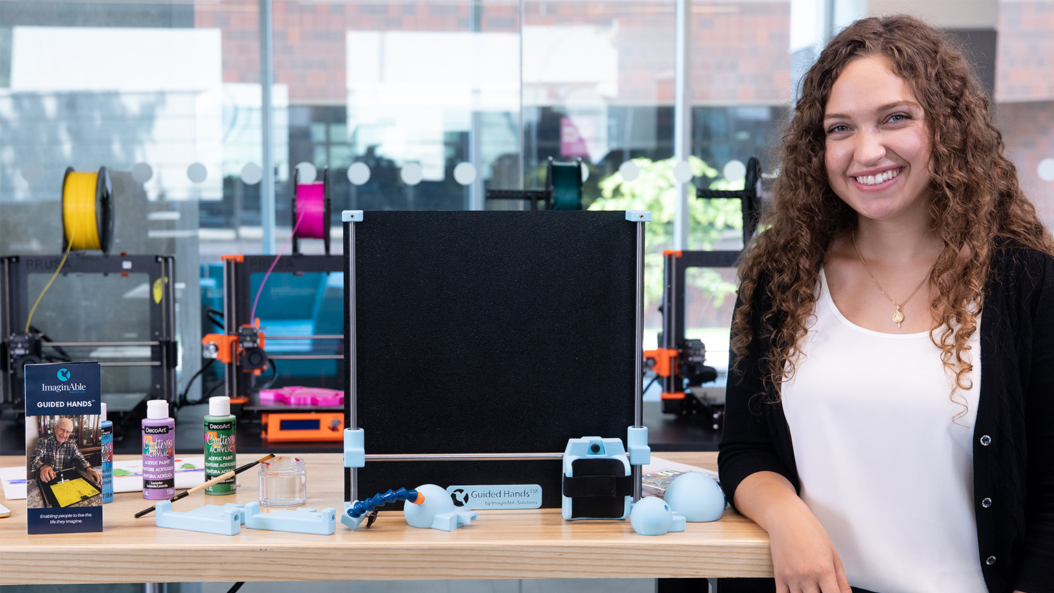 Lianna stands beside her guided hands device in the iBioMed Design Studio