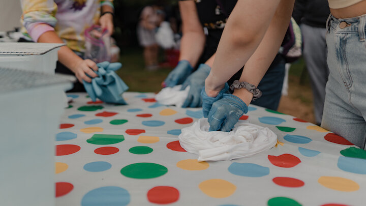 gloved hands wrapping white t-shirts into tight wads.