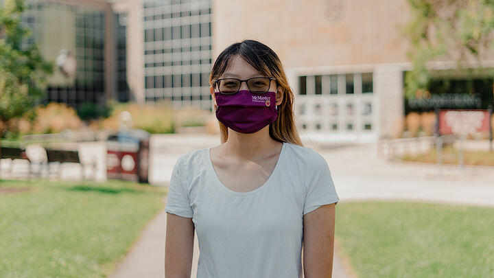 Person standing outside wearing a McMaster University branded maroon cloth mask.