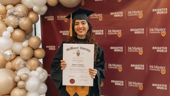 Leila Mousapour holds her degree and smiles.