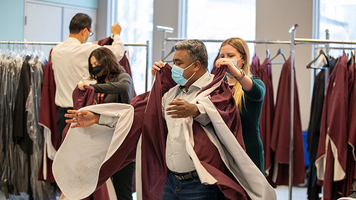 Someone helps Mohammad Chowdhury put his graduation robes on.