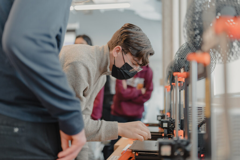 A student bent over using a 3D printer