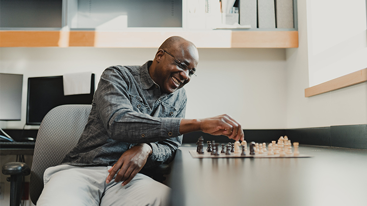 Paulin Coulibaly smiles as he plays chess.