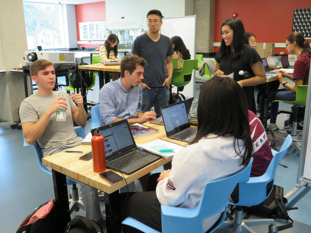 group of students engaged in lively conversation around a table