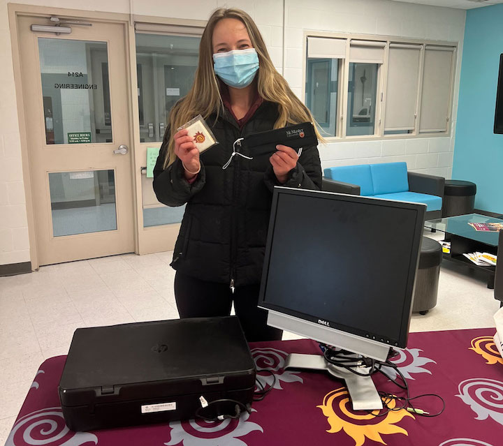 A person drops off a monitor and grabs a cookie and mcmaster face mask as a reward