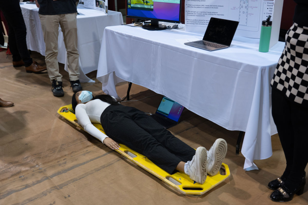 Spinosense capstone display: A woman lies on a spinal board that has sensors that tracks pressure points