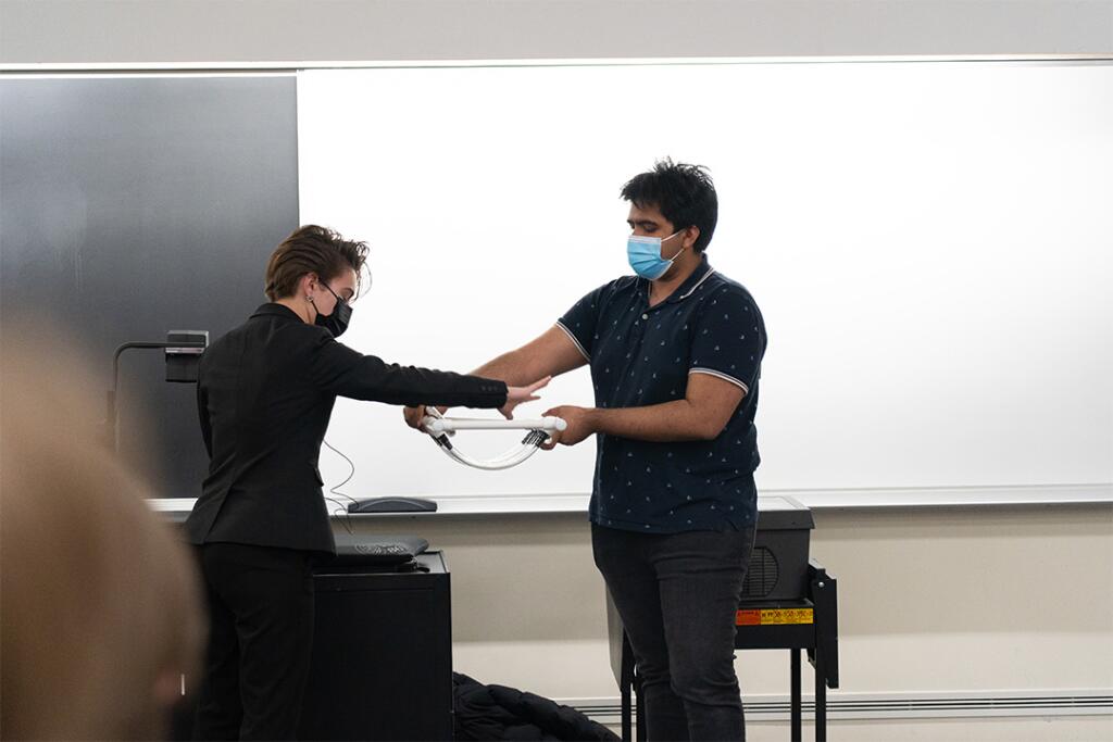 Two students demonstrate their invention that helps a person wash dishes.