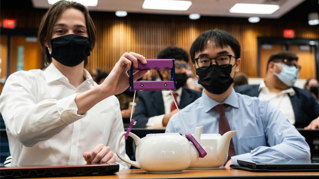 Two students demonstrate Handular, a device that helps pour a teapot.