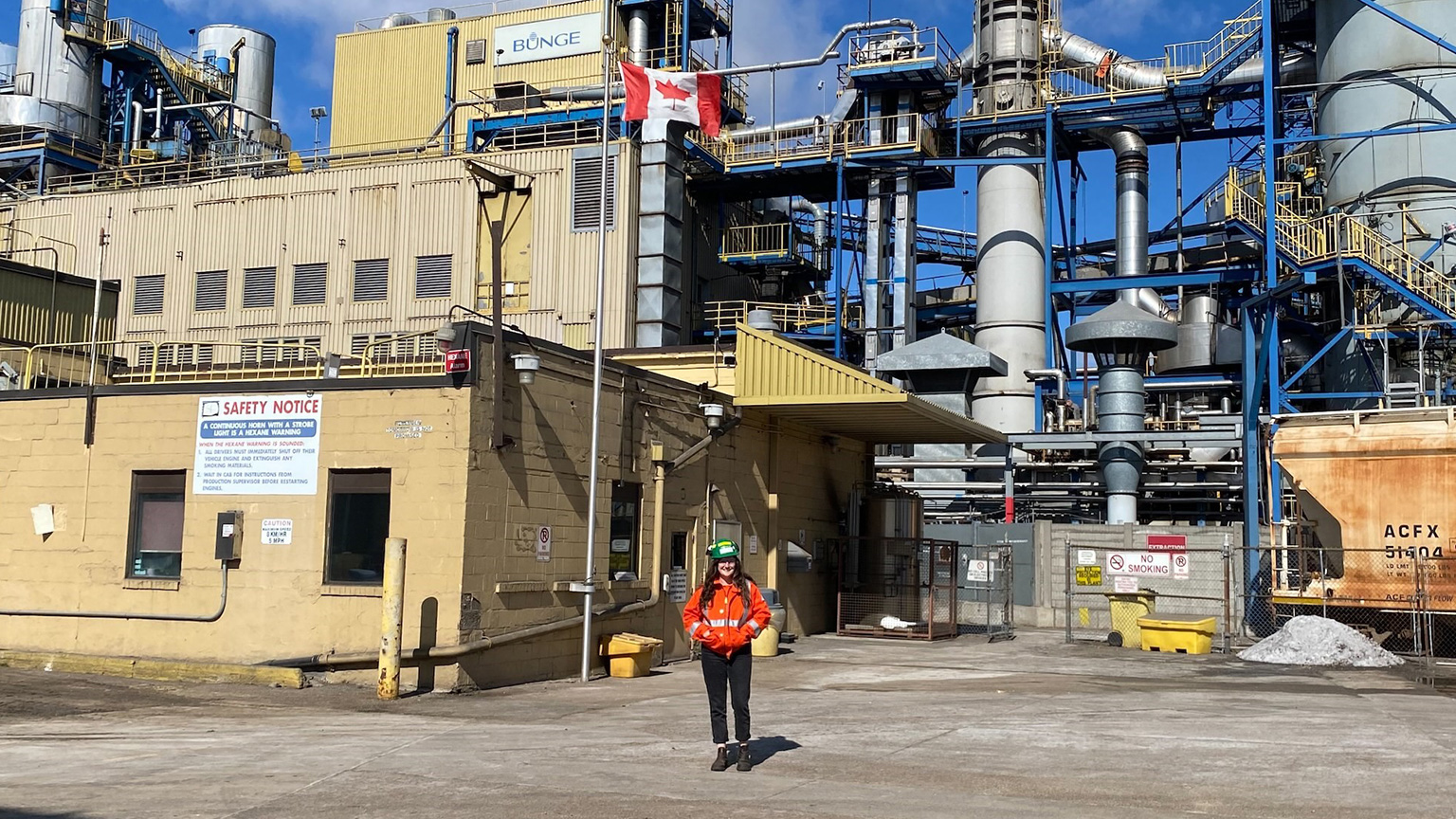 Shayna Earle stands in front of Bunge wearing a safety vest and hard hat