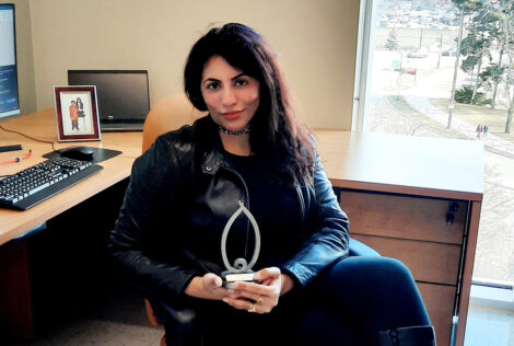 Zobia Jawed sits in her office holding her YWCA Women of Distinction award