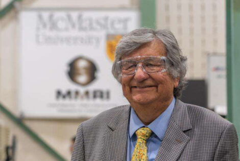 Barry Hill smiles while wearing safety glasses in front of a McMaster MMRI banner.