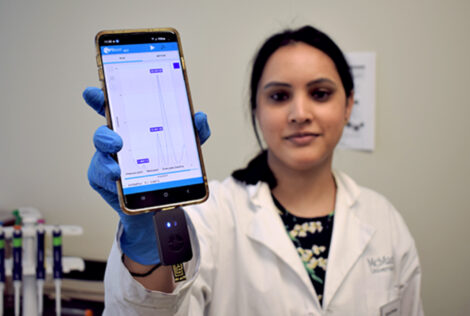 Postdoc Richa Pandey holds up a smartphone with test results on the screen.
