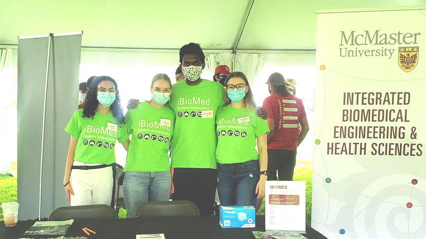 A group of students wearing bright green ibiomed shirts pose for a photo