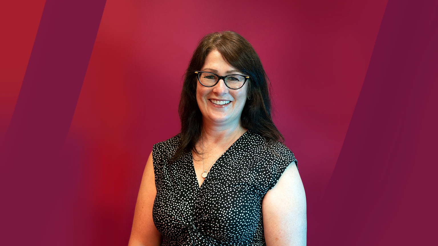 Sarah Dickson-Anderson poses in front of maroon backdrop