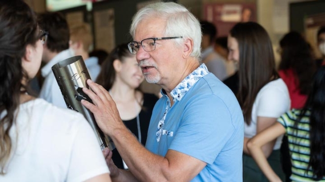 Joh Preston holds a torch designed by Mac Eng students while talking to a student