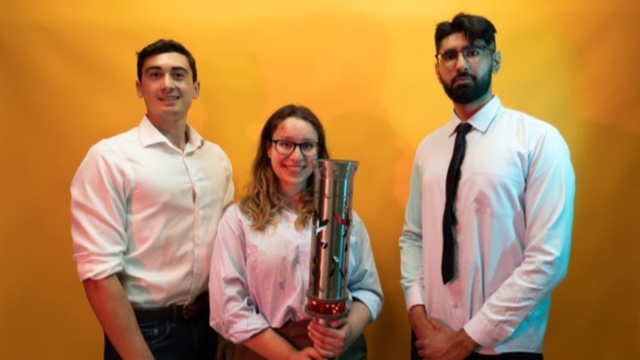 three people posing with a torch.