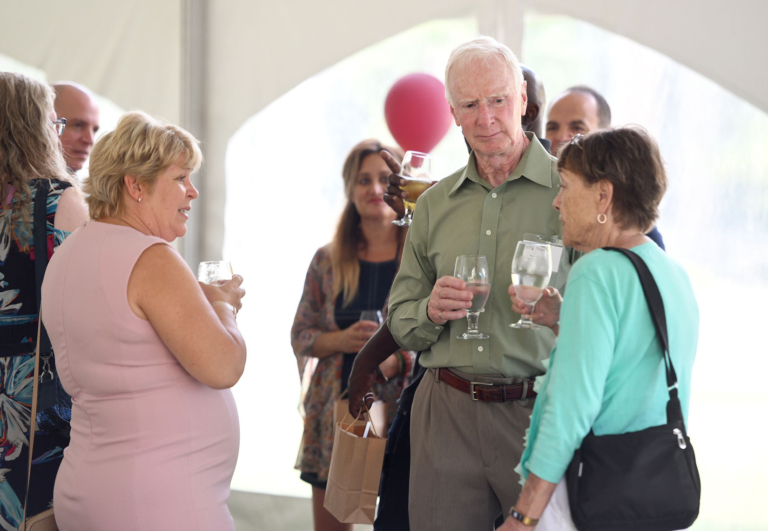 Heather Sheardown speaks with two graduates in an outdoor tent
