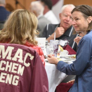 two women speaking to each other, a Mac Chem Eng jacket hangs off one of the chairs they are sitting in