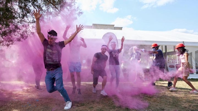 group of people running through purple powder.