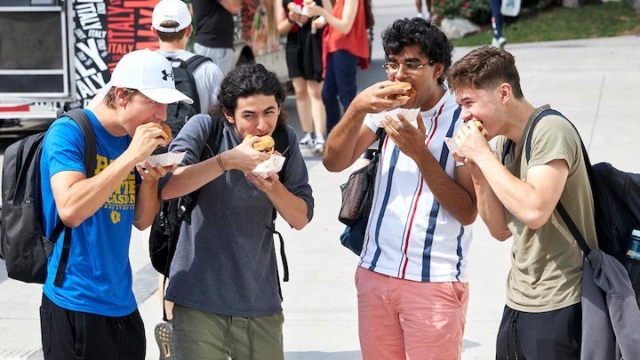 four boys outside eating hotdogs.