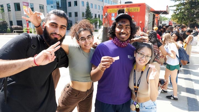 four people posing for a picture with the Dirty South food truck in the background